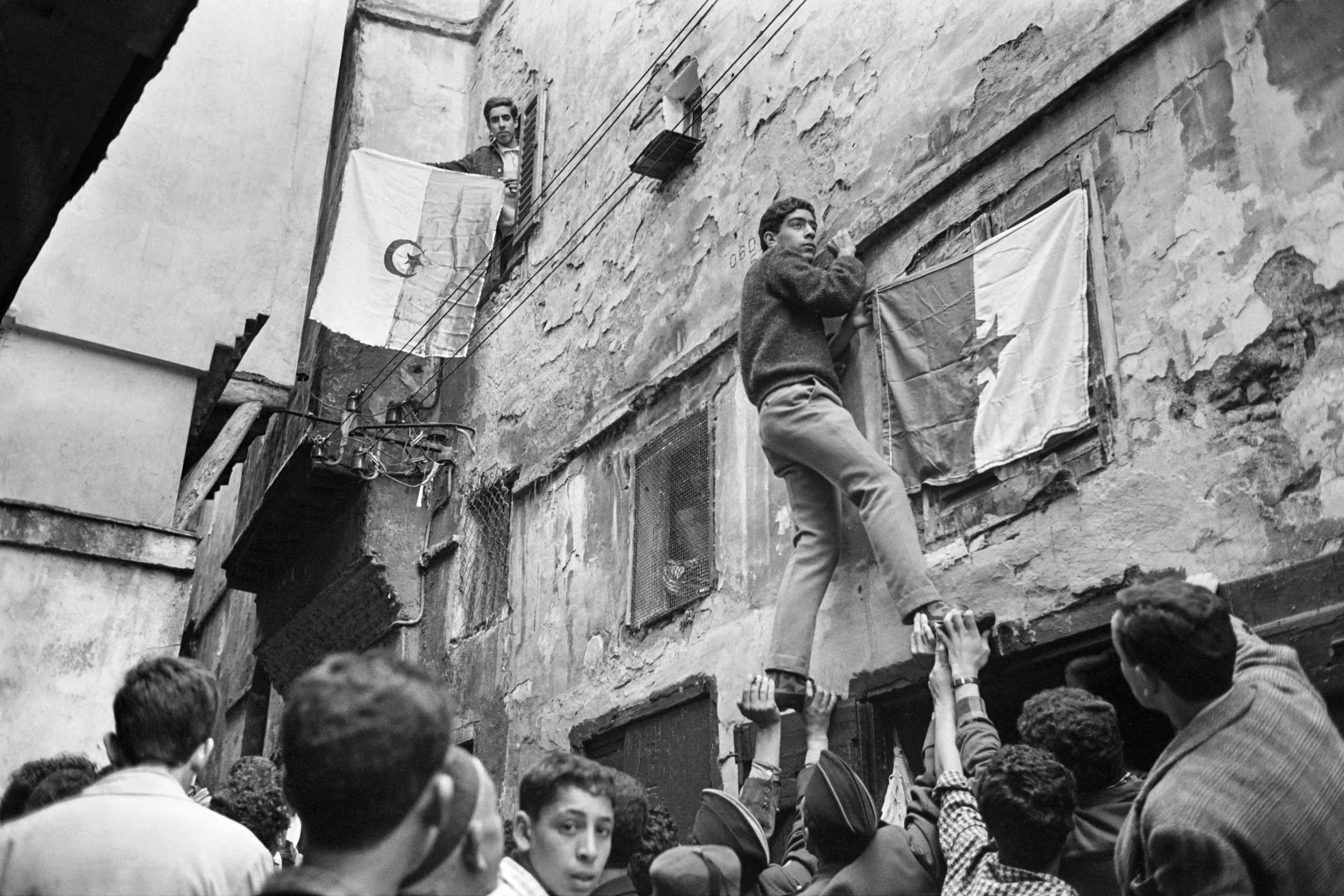 Молоді алжирці вивішують національний прапор на стіні цитаделі Касбах 6 липня 1962 року, через день після проголошення незалежності Алжиру. Деколонізація