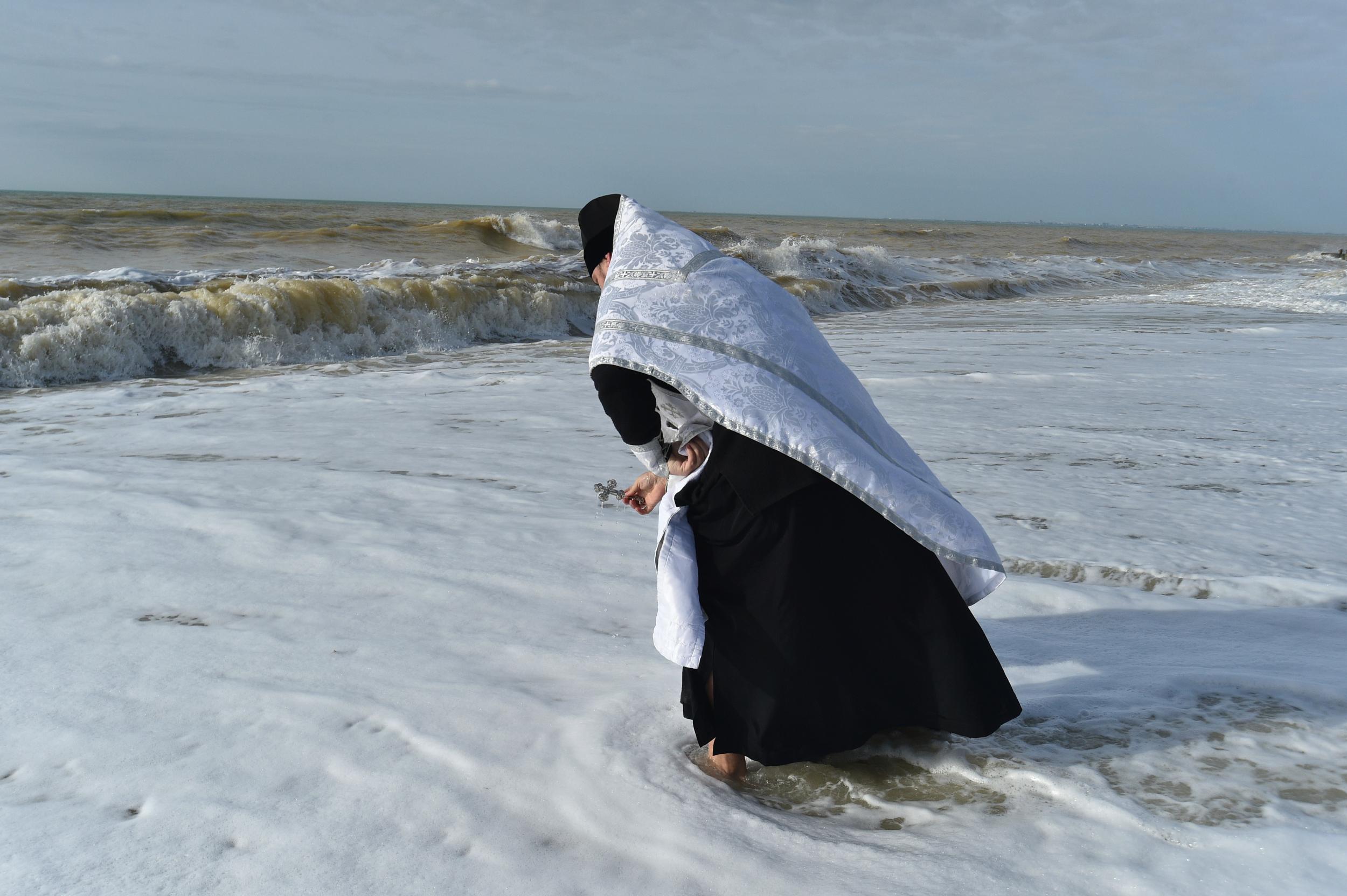 Священник освячує воду Чорного моря під час свята Водохреще в місті Саки, Крим, 19 січня 2023 року.