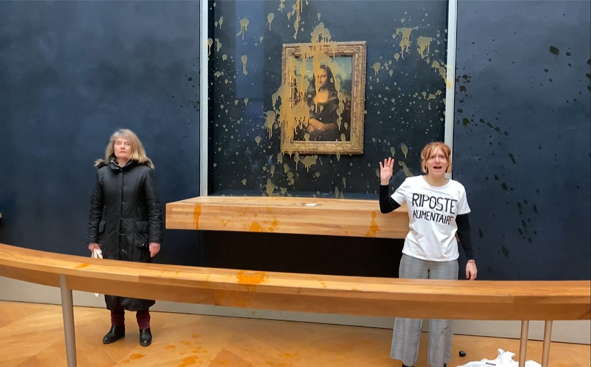 Двоє екологічних активісток з групи «Riposte Alimentaire» («Продовольча відплата») стоять перед картиною Леонардо да Вінчі «Мона Ліза» (La Joconde) після того, як кинули в неї суп в музеї Лувр у Парижі, 28 січня 2024 року. Протестувальниці кинули суп у куленепробивне скло, що захищає «Мону Лізу», вимагаючи права на «здорову їжу, яка на шкодить довкіллю», повідомив журналіст AFP. Це останній напад на шедевр у французькому Луврі після того, як у травні 2022 року хтось кинув у нього заварний пиріг. Через товстий скляний корпус картина не постраждала. Фото: DAVID CANTINIAUX/AFPTV/AFP via Getty Images