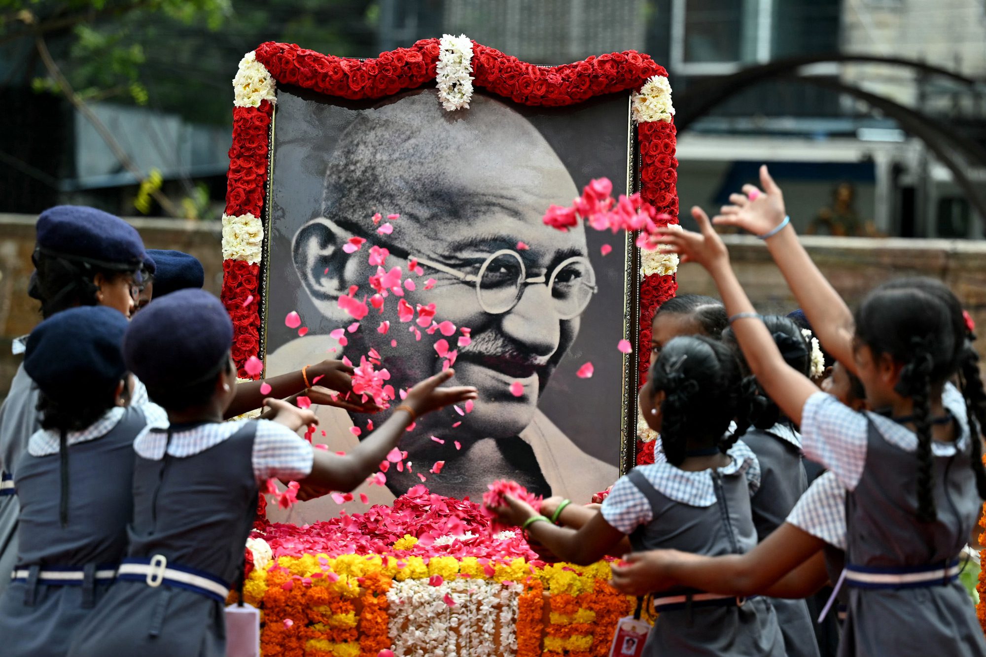 Індійські школярі кидають пелюстки троянд на портрет Махатми Ганді, щоб віддати данину пам'яті в річницю смерті батька-засновника Індії, в місті Ченнай, 30 січня 2024 року. Річниця смерті Ганді, відомого в Індії як Бапу (батько), також відзначається в країні як День мучеників. Фото: SATISH BABU/AFP via Getty Images